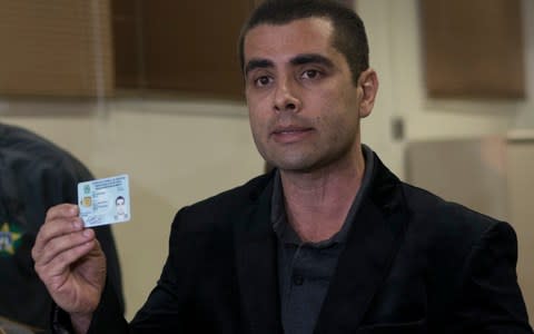 Brazilian "celebrity" surgeon Dr. Denis Cesar Barros Furtado shows his doctors license as he speaks to the press at the police department - Credit: AP