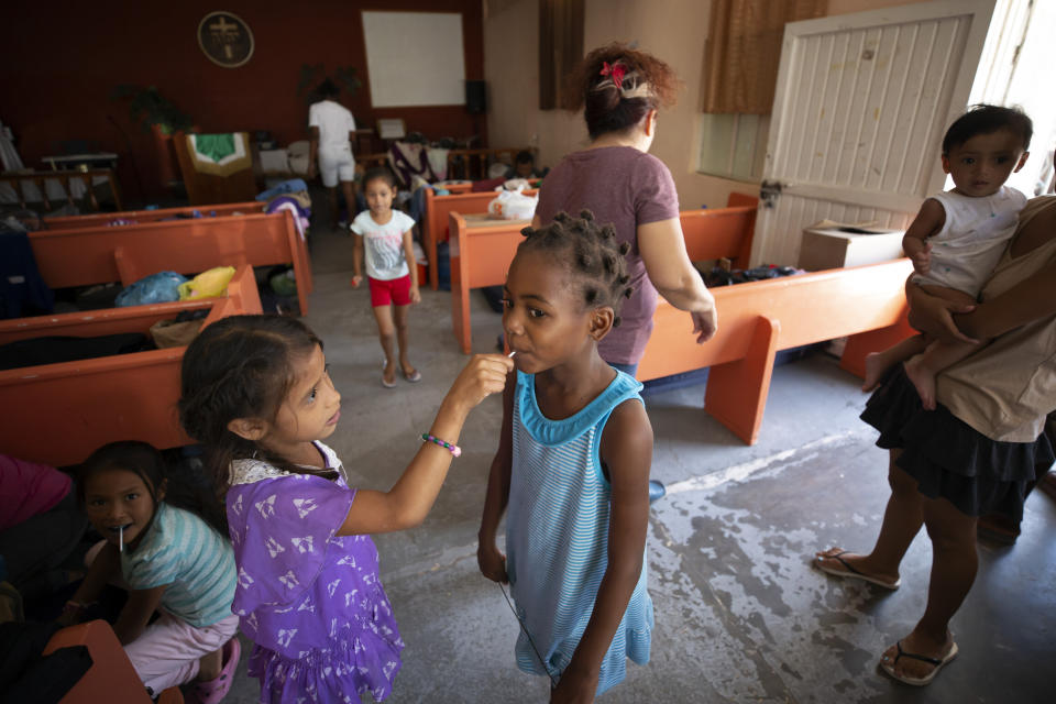 In this July 25, 2019, photo, a Honduran girl shares a lollipop with an African girl at El Buen Pastor shelter for migrants in Cuidad Juarez, Mexico. (AP Photo/Gregory Bull)