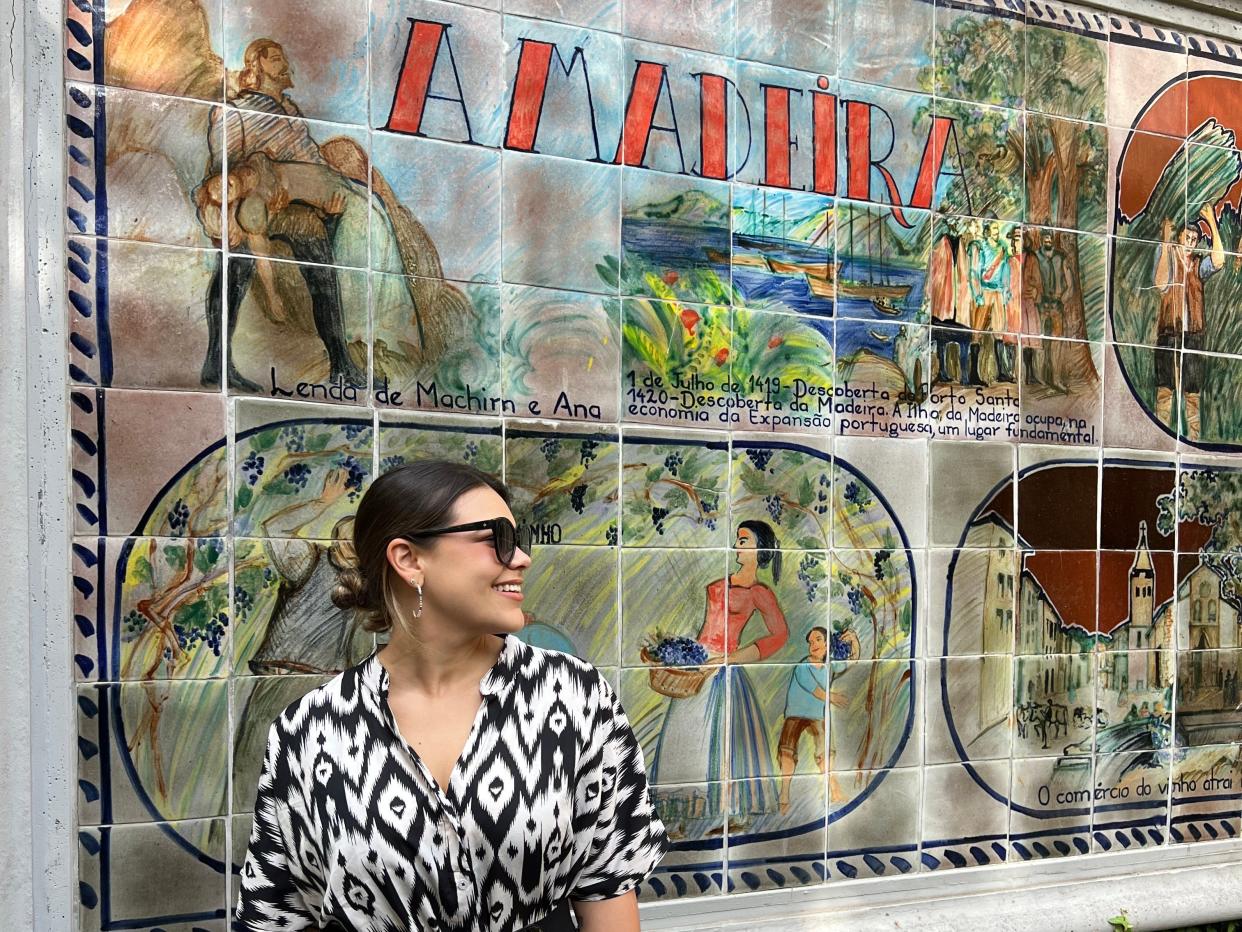 Victoria poses in front of a mural that says "Madeira."