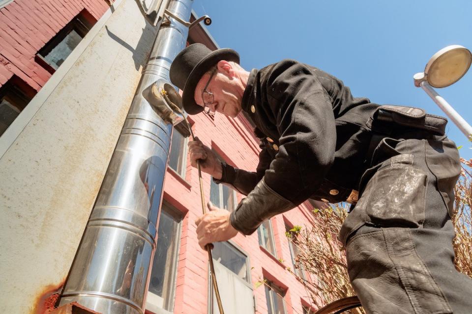 Schornsteinfegermeister Lutz-Matthias Peters prüft einen Schornstein mit einem flexiblen Besen auf Verstopfungen. In diesen Wochen haben Schornsteinfeger besonders viel zu tun – als Energieberater.  - Copyright: picture alliance/dpa/Markus Scholz