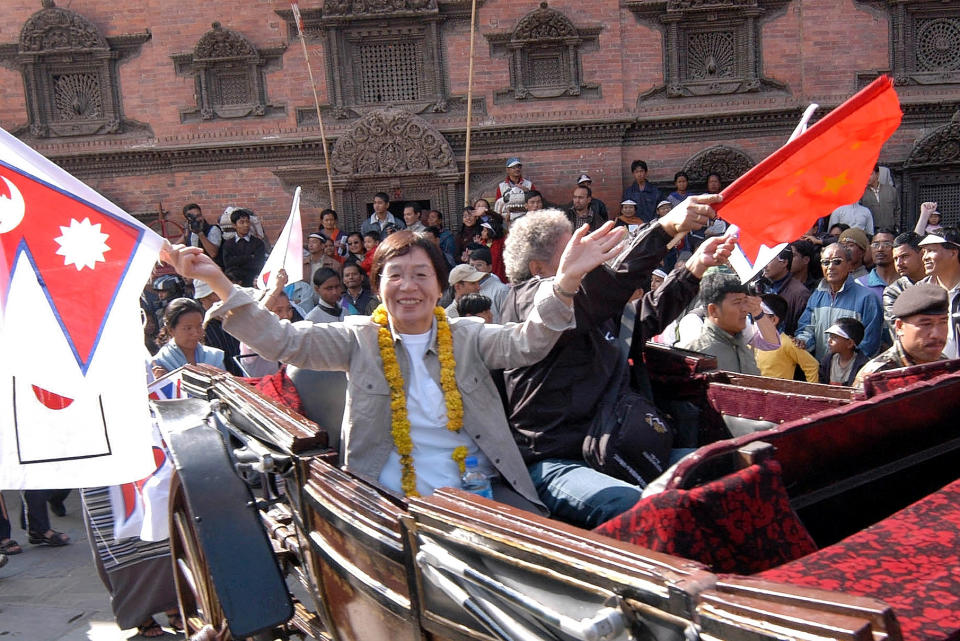 Junko Tabei, left, first woman to climb Mount Everest, waves flags of Japan and Nepal during a reception hosted in her honor in Katmandu in 2005. (AP photo/Binod Joshi)