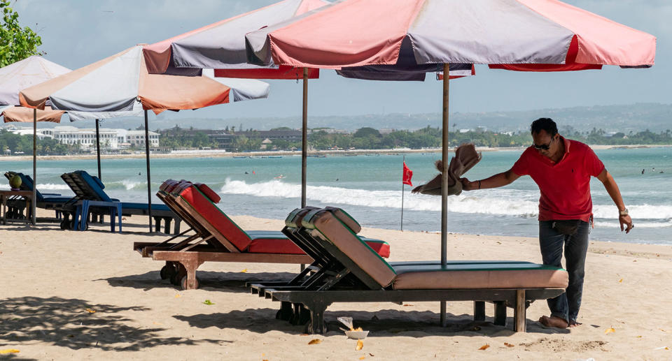 Man cleaning beach chair on Bali beach. Source: EPA