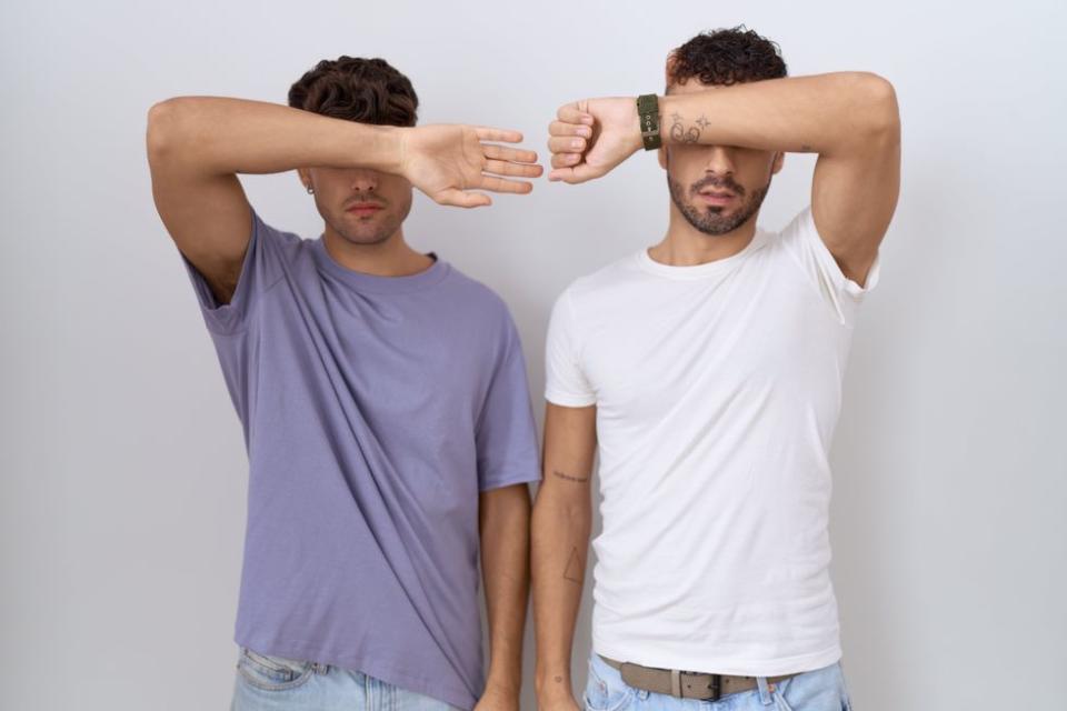 two men covering their eyes