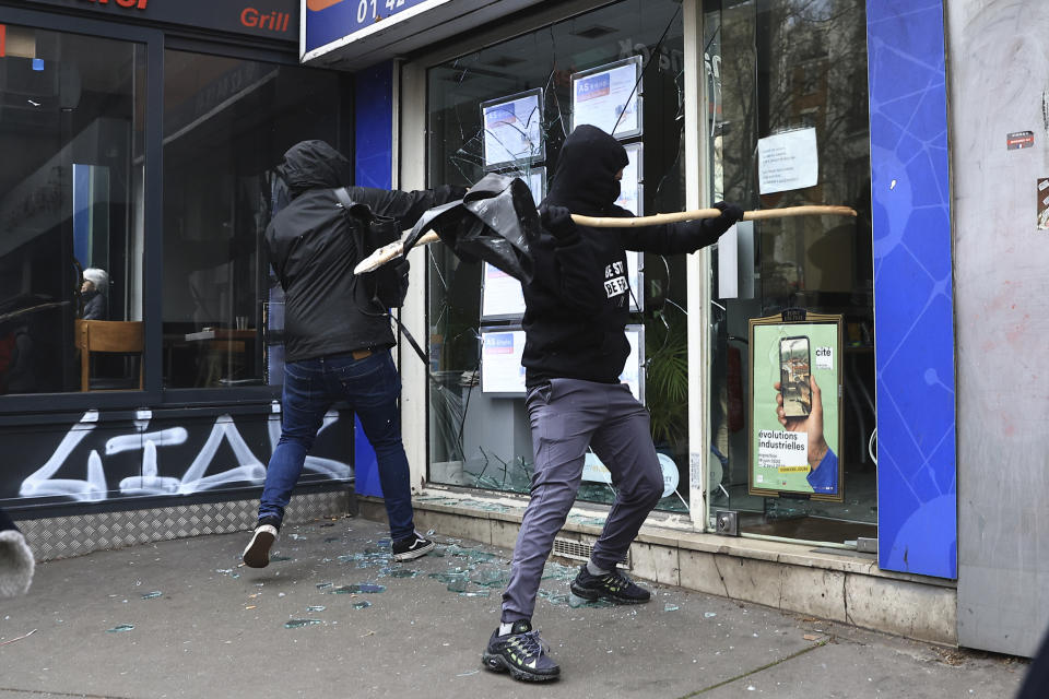 Protesters smash a shop window during a demonstration against the government's plan to raise the retirement age to 64, in Paris, France, Wednesday, March 15, 2023. Opponents of French President Emmanuel Macron's pension plan are staging a new round of strikes and protests as a joint committee of senators and lower-house lawmakers examines the contested bill. (AP Photo/Aurelien Morissard)