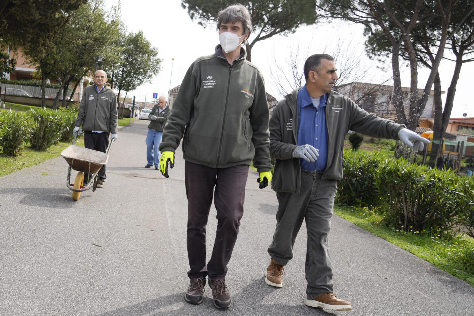 From left, Vittorio Masi, Fabrizio Fiore and Giorgio Cavalieri stroll along the gardens of the Chicco community of L'Arche, an International charity that helps people with intellectual disabilities, in Ciampino, near Rome, Wednesday, March 22, 2023. The findings of expert reports commissioned by L’Arche itself reveal that their founder, Jean Vanier, perverted Catholic doctrine to justify his own sexual compulsions and abuse women and that the movement he created had at its core a secret, a mystical-sexual “sect” founded for the precise purpose of hiding the sect’s deviant activities from church authorities. (AP Photo/Gregorio Borgia)