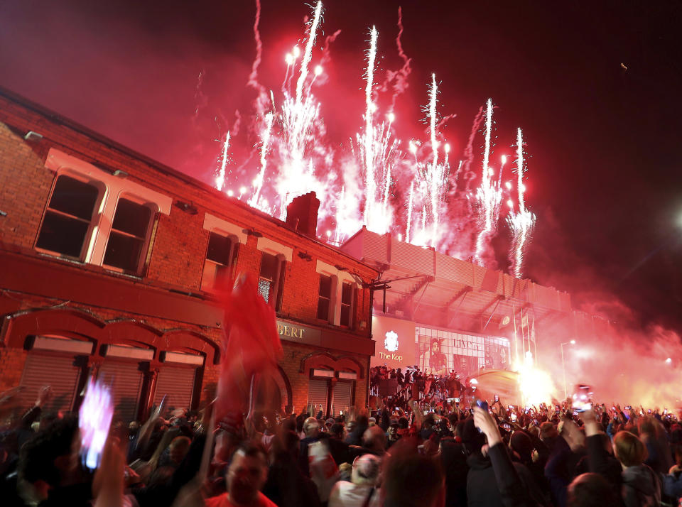 Liverpool fans celebrate outside Anfield stadium as fireworks are set off as the players receive the Premier League trophy inside the grounds after the English Premier soccer match between Liverpool and Chelsea, Wednesday, July 22, 2020, in Liverpool, England. (Martin Rickett/PA via AP)