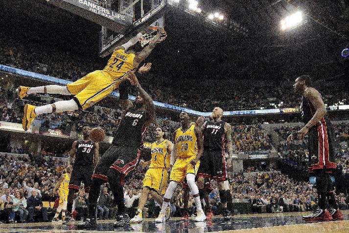 Indiana Pacers forward Paul George (24) hangs on the rim after dunking in front of Miami Heat forward LeBron James (6) during the second half of an NBA basketball game in Indianapolis, Wednesday, March 26, 2014. The Pacers won 84-83. (AP Photo/AJ Mast)