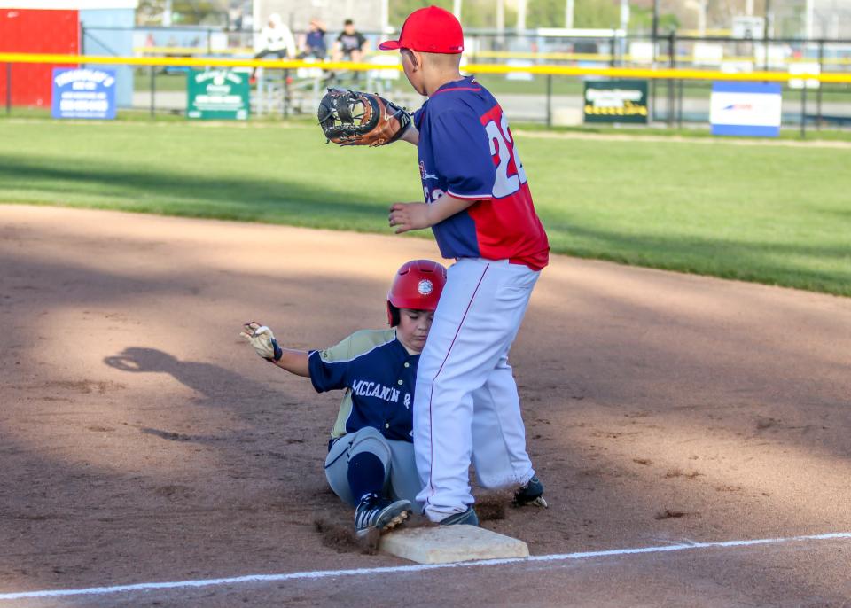Ethan Dube of McCann & Son's slides into first base in front of Wonder Bowl's Kaleb Braga to avoid being doubled up on Thursday evening at Whaling City Youth Baseball League in New Bedford's North End.