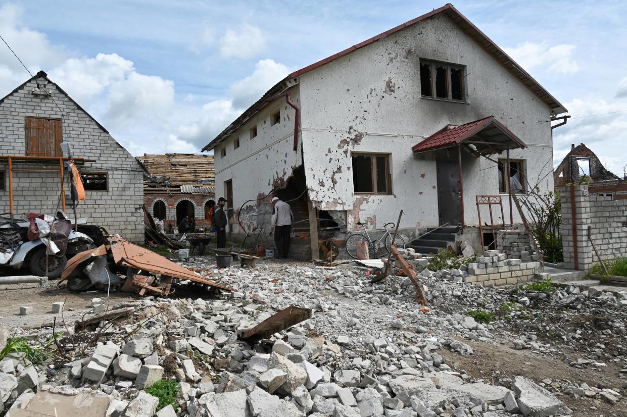 Local residents stand next to a  heavily damaged residential house in Mala Rogan, one of the villages east of Kharkiv where Russian reports of brutalities are alleged to have taken place. (Getty)