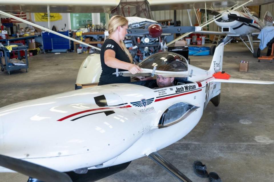 Jen Watson fits the canopy over her husband Josh on Wednesday, Sept. 6, 2023, as they demonstrate how they fit in the cockpit of one of their racing planes in the hangar at their home in Wilton. The plane has been partially disassembled for transportation in a trailer to the final running of the Reno Air Races, which the married pilots will compete in starting Sept. 13.