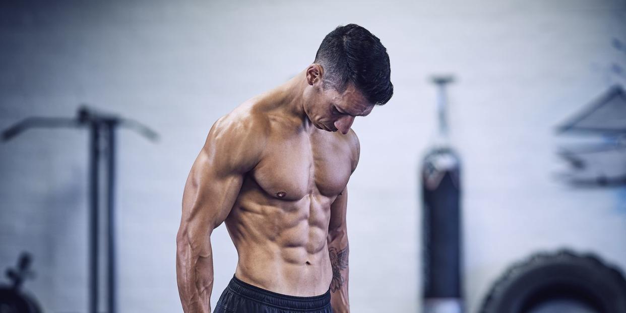 muscular male bodybuilder in industrial gym holding dumbbells