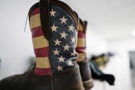 Boots decorated with the stars and stripes of a U.S. flag, and other shoes sit in an employee area inside the Hanwha Qcells Solar plant, Monday, Oct. 16, 2023, in Dalton, Ga. The Korean company is opening what it says is the first solar panel factory to begin production in the U.S. since the passage of President Joe Biden’s signature climate legislation. (AP Photo/Mike Stewart)