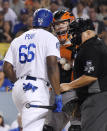 Los Angeles Dodgers' Yasiel Puig, left, and San Francisco Giants catcher Nick Hundley, center, argue while home plate umpire Eric Cooper gets between them during the seventh inning of a baseball game, Tuesday, Aug. 14, 2018, in Los Angeles. (AP Photo/Mark J. Terrill)