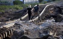 A couple walks across railroad tracks covered by flood debris in Longmont, Colorado September 16, 2013. Seven people were confirmed dead and at least 1,500 homes destroyed in Colorado after a week of rare, torrential rains along the eastern slopes of the Rockies, and helicopter search-and-rescue flights resumed on Monday in flood-stricken areas. (REUTERS/Rick Wilking)