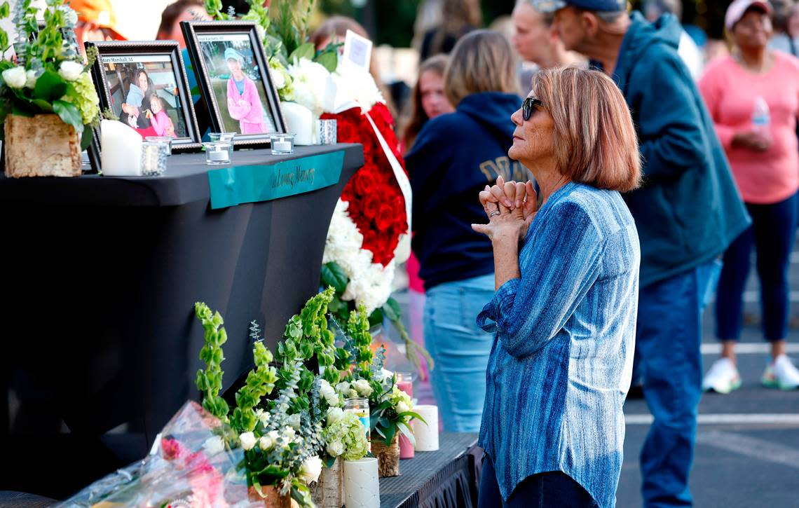 After a candlelight vigil outside the Hedingham clubhouse Saturday, Oct. 15, 2022, attendees look at a memorial for those killed and wounded in a mass shooting in the Hedingham neighborhood in Raleigh, N.C., on Thursday.