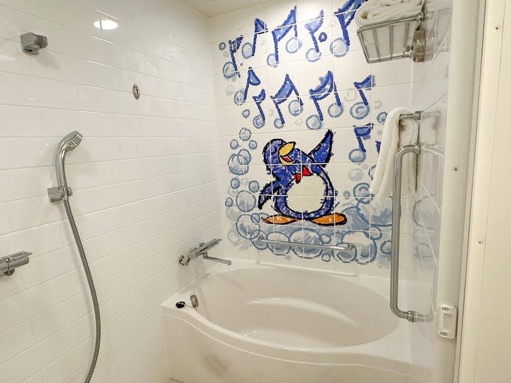 A guest bathroom at Tokyo's Toy Story Hotel features file with a Wheezy character singing in the tub with blue bubbles and music notes surrounding him.
