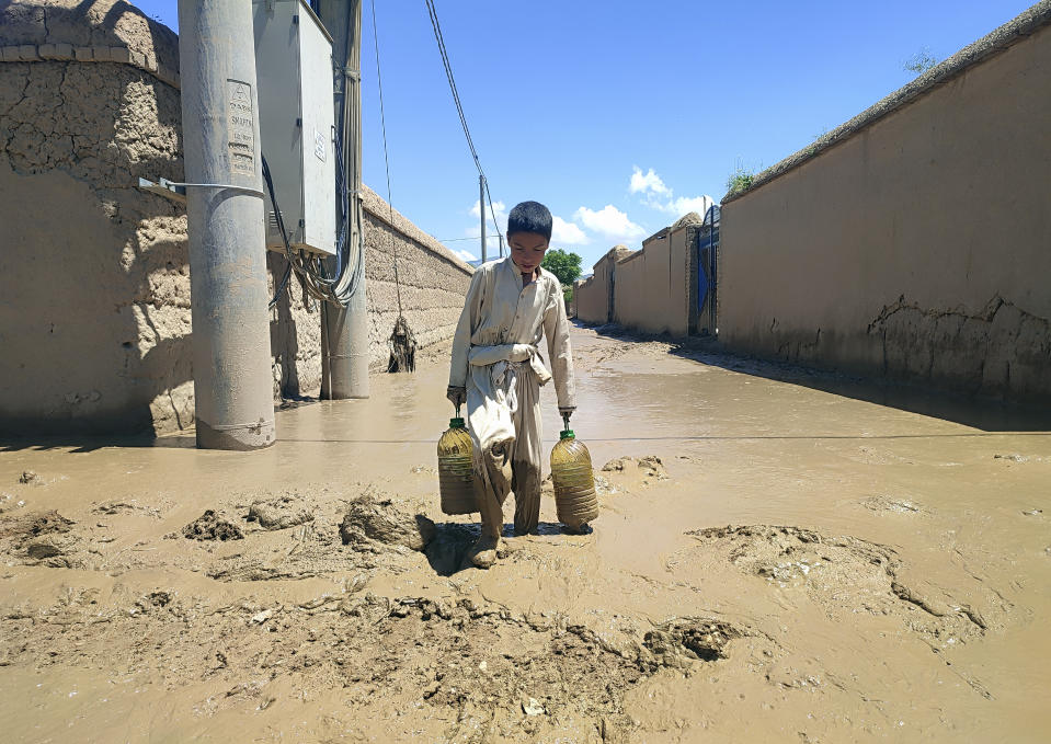 An Afghan boy carries oil through muddy water, after heavy flooding in Baghlan province in northern Afghanistan Sunday, May 12, 2024. Victims of the devastating floods in northern Afghanistan are burying the dead and looking for the loved ones still missing. (AP Photo)