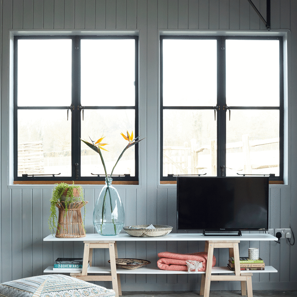 Two large windows in blue wall with TV