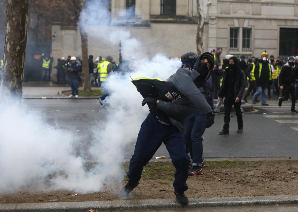 A demonstrator throws an item to police forces after a march Saturday, Jan. 19, 2019 in Paris. Thousands of yellow vest protesters rallied Saturday in several French cities for a 10th consecutive weekend, despite a national debate launched this week by President Emmanuel Macron aimed at assuaging their anger. (AP Photo/Thibault Camus)