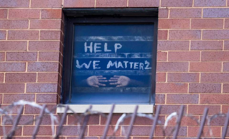 An inmate in the maximum security unit of the Cook County Jail in Chicago presses his hands against the window, below a plea for help.