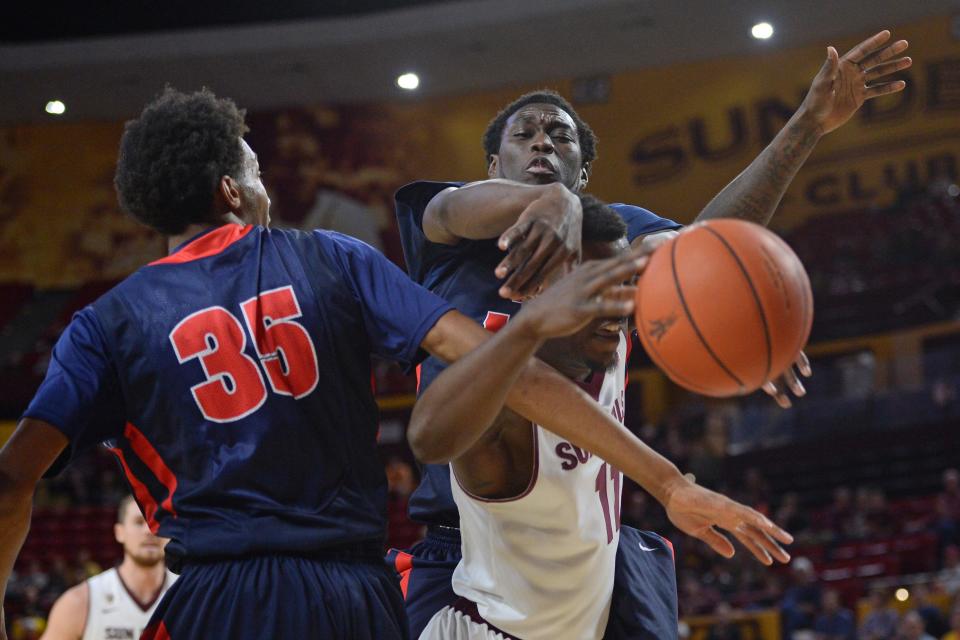 Detroit's Paris Bass and Youssoupha Kane defend Savon Goodman during the first half at Wells-Fargo Arena in Tempe.