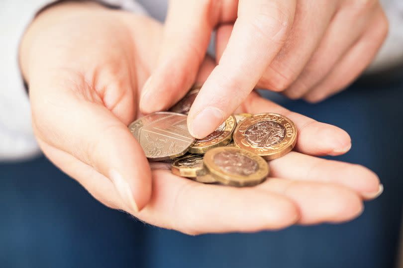 Close-up of a woman's hands as she takes a 50p coin from her hand to make a payment.