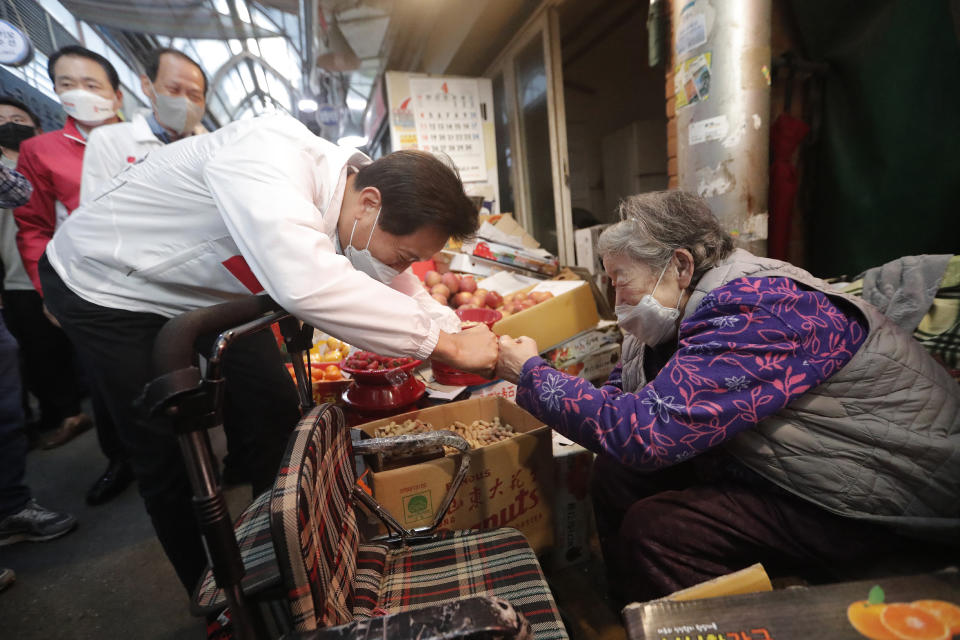 Oh Se-hoon, left, the candidate of the main opposition People Power Party, bumps fists with a vendor during a campaign for the April 7 Seoul mayoral by-election at a market in Seoul, South Korea, Tuesday, April 6, 2021. (AP Photo/Ahn Young-joon)