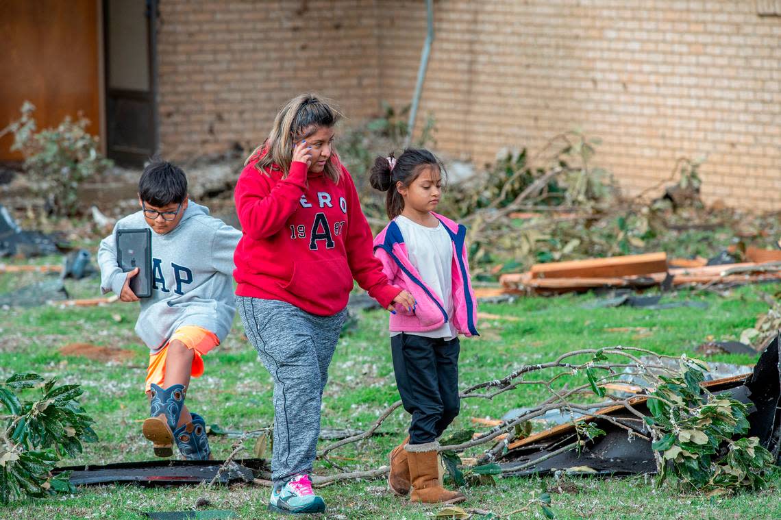 Damien Gonzalez, his mom, Issabella, and sister, Isa, walk across their front yard after a torando destryed their home Tuesday, Dec. 13, 2022.
