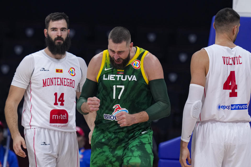 Lithuania center Jonas Valanciunas (17) celebrates a basket between Montenegro centers Bojan Dubljevic (14) and Nikola Vucevic (4) during the second half of a Basketball World Cup group D match in Manila, Philippines Tuesday, Aug. 29, 2023.(AP Photo/Michael Conroy)