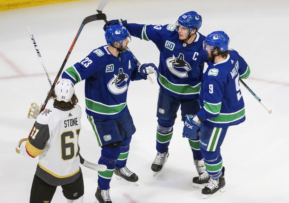 Vegas Golden Knights' Mark Stone (61) skates past as Vancouver Canucks' Alexander Edler (23), Bo Horvat (53) and J.T. Miller (9) celebrate a goal by Horvat during the second period of an NHL Western Conference Stanley Cup playoff game, Sunday, Aug. 30, 2020, in Edmonton, Alberta. (Jason Franson/The Canadian Press via AP)