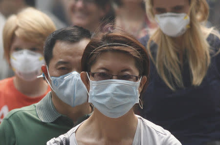 People wearing masks cross a street in Singapore's Orchard Road Shopping Area in this June 21, 2013 file photograph. REUTERS/Edgar Su/Files