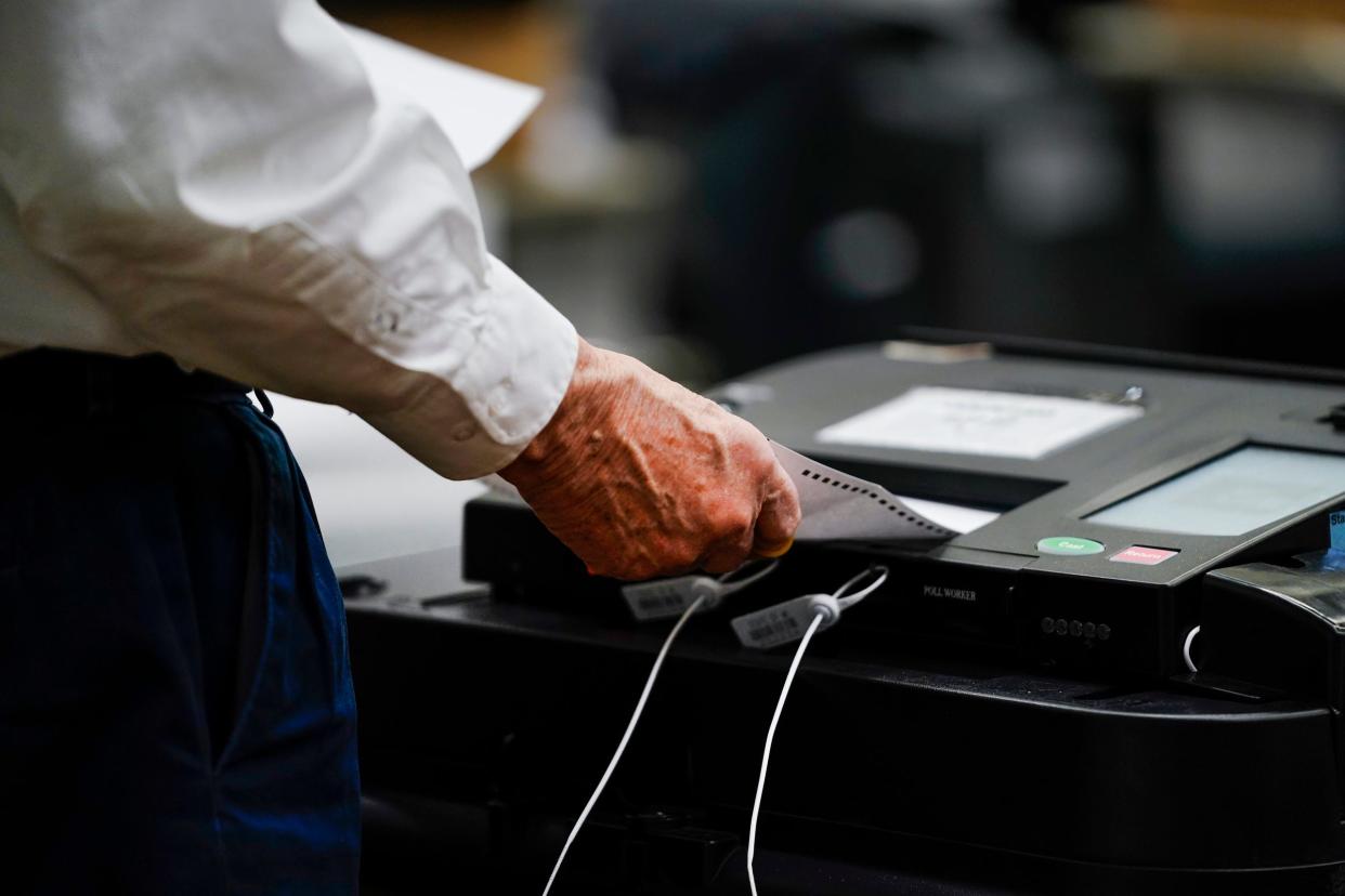 An election official feeds an absentee ballot through a tabulator as he helps to count Detroiters votes at Huntington Place for the presidential primary on Tuesday, Feb. 27, 2024.