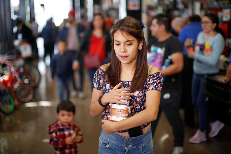 A woman carries loose items as she leaves a supermarket which no longer provides plastic bags for customers to carry products, in Mexico City