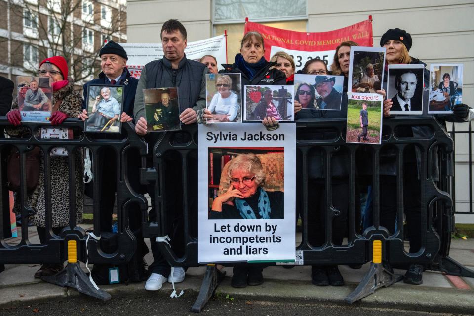 People hold banners as they protest after the arrival of Boris Johnson, Britain's former Prime Minister, at the Covid Inquiry on Wednesday (Getty Images)