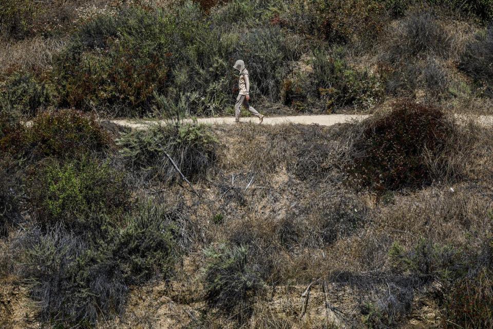 A man hikes a trail at Eaton Canyon in temperatures above 100 degrees.