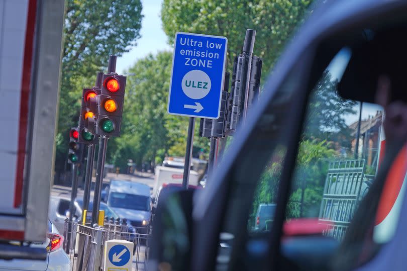Traffic and an information sign for the Ultra Low Emission Zone (Ulez) on Brownhill Road in Lewisham, south London