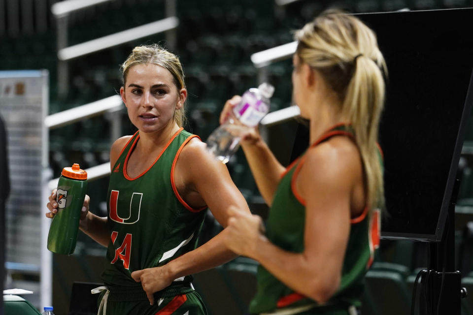 FILE - Miami NCAA college basketball guards and sisters, Haley and Hanna Cavinder, take a break during practice Friday, Oct. 7, 2022, in Coral Gables, Fla. Haley and Hanna Cavinder are going to the NCAA Tournament. The Miami guards are perhaps the faces of the NIL movement in college athletics. And they have a massive following on social media. (AP Photo/Matt Dirksen, File)