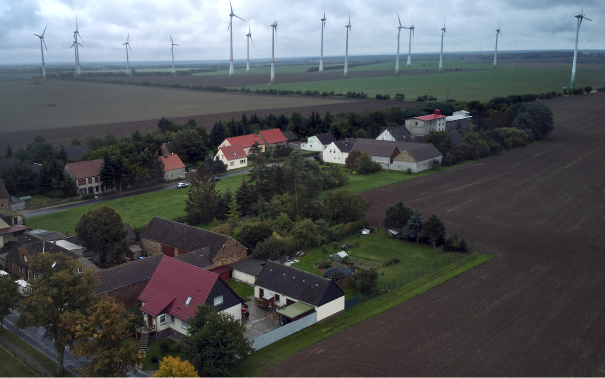Wind turbines turn near the village of Feldheim, rear left, near Treuenbrietzen, Germany. Located about an hour and a half south of Berlin, the village of Feldheim has been energy self-sufficient for more than a decade. (AP Photo/Michael Sohn)