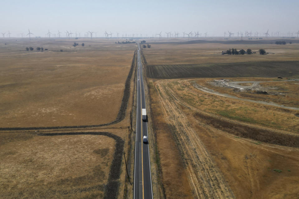 In this aerial photo traffic runs along Highway 113 in rural Solano County, Calif., with wind farms in the background Wednesday, Aug. 30, 2023. Silicon Valley billionaires and investors are behind a years-long, secretive land buying spree of more than 78 square miles (202 square kilometers) of farmland in Solano County with the goal of creating a new city.(AP Photo/Terry Chea)