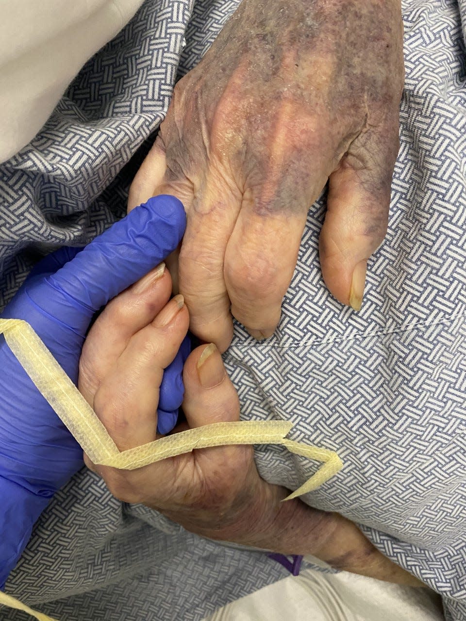 Evelyn Watts grips the hands of her granddaughter, Micaela Watts, in the last minutes of her life. Evelyn died of COVID-19 on April 19, 2021.