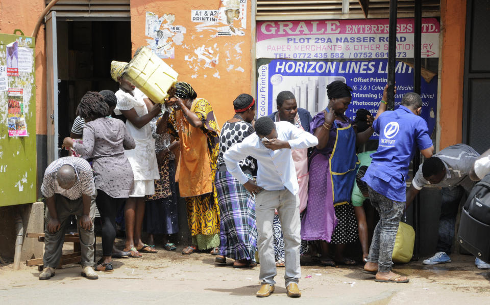Ugandan shop traders and protesters recover from the effects of tear gas in Kampala, Uganda Monday, Aug. 20, 2018. Ugandan police fired bullets and tear gas to disperse a crowd of protesters demanding the release of jailed lawmaker, pop star, and government critic Kyagulanyi Ssentamu, whose stage name is Bobi Wine. (AP Photo/Ronald Kabuubi)