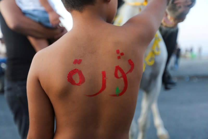 A boy has the word "revolution" written on his back during an anti-government protest in the southern city of Tyre