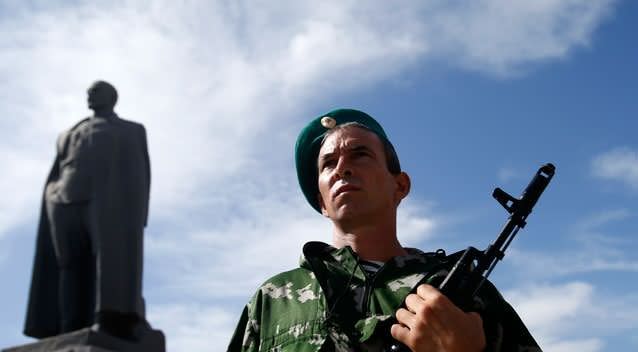 A pro-Russian gunman guards a monument to Soviet security police founder Felix Dzerzhinsky in the town of Luhansk, eastern Ukraine, Sunday, Sept. 14, 2014. Photo: Getty