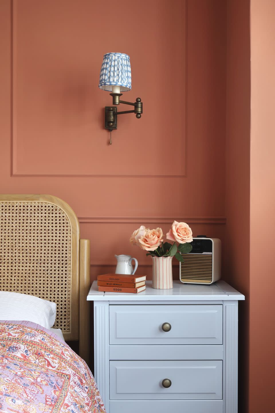 orange bedroom with pale blue bedside table and paisley bedspread