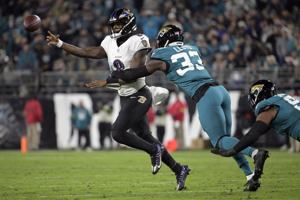 Baltimore Ravens quarterback Lamar Jackson (8) gets a pass away as he is pressured by Jacksonville Jaguars linebacker Devin Lloyd (33) in the first half of an NFL football game Sunday, Dec. 17, 2023, in Jacksonville, Fla. (AP Photo/Phelan M. Ebenhack)