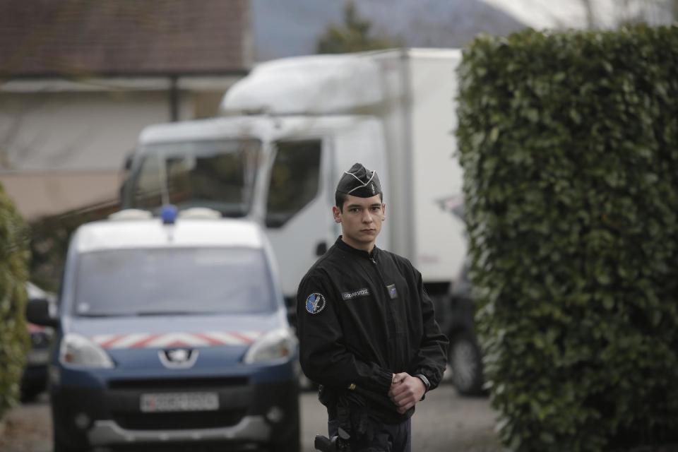 A French gendarme blocks the access to a house in a residential area in Talloires, French Alps, Tuesday, Feb. 18, 2014, as part of the continuing investigation into the grisly shooting deaths of a British-Iraqi man and three others nearly 18-months ago. French police announced Tuesday they have detained a 48-year old man, a resident of eastern France, in connection with the deaths. (AP Photo/Laurent Cipriani)