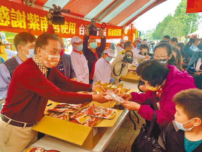 紫南宮主委莊秋安（左），發送丁酒（麻油雞）冷凍調理包給民眾。（廖志晃攝）