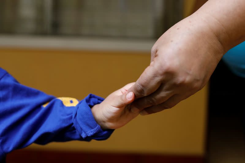 An unaccompanied child who was deported from the U.S. touches hands with his carer at a shelter in Guatemala City