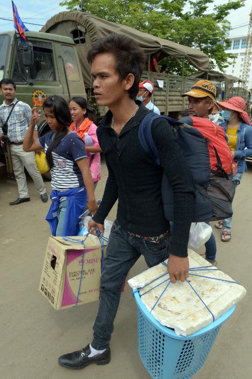 Cambodian migrant workers who recently crossed the border carry their belongings after arriving in the city of Poipet on the Thai-Cambodian border, on June 18, 2014