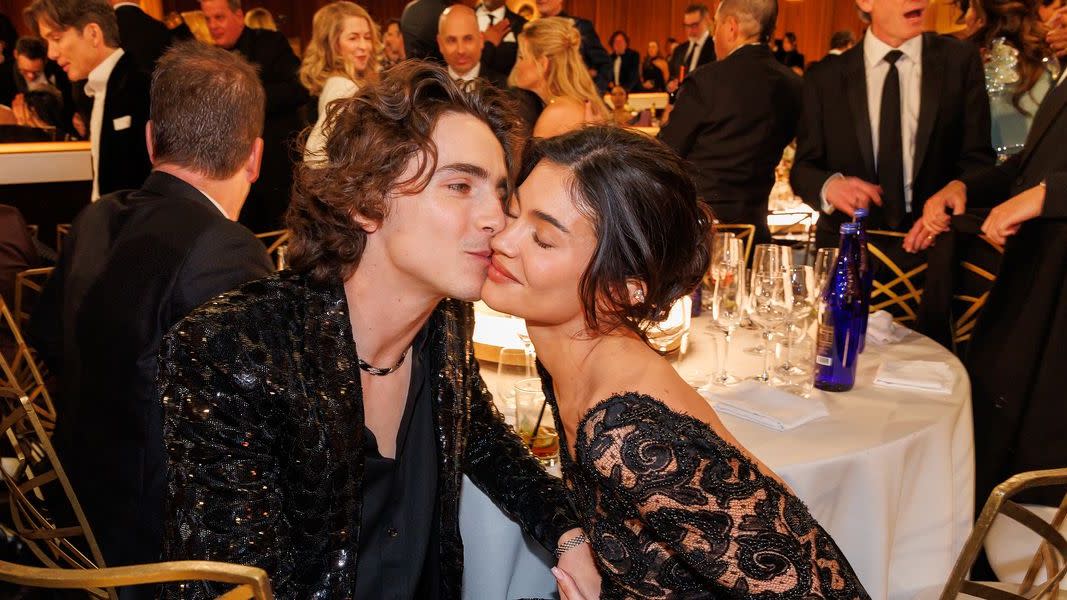 a couple of women kissing at a dinner table